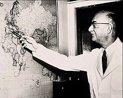Dr. Dameshek points to a world map.